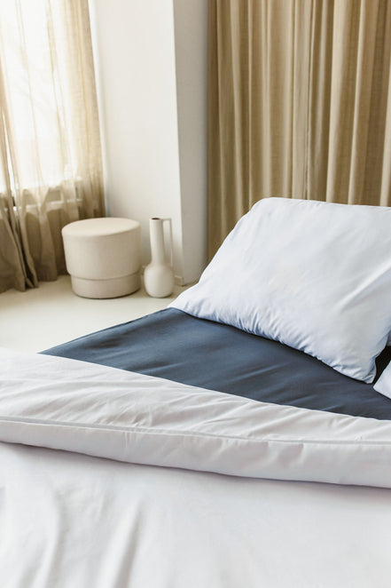 Opgemaakt bed met wit kussensloop en wit dekbedovertrek